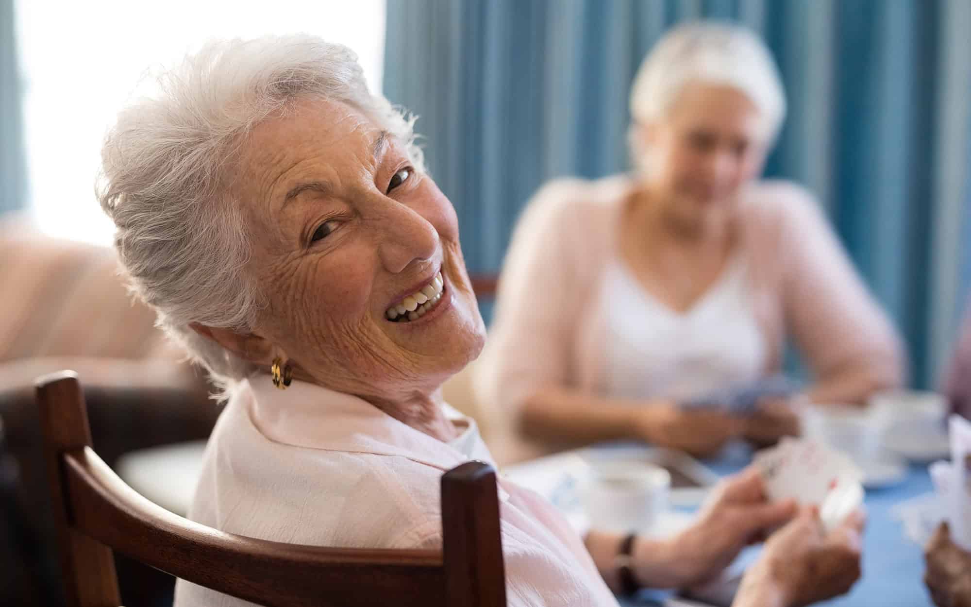 Smiling senior woman playing cards with friends